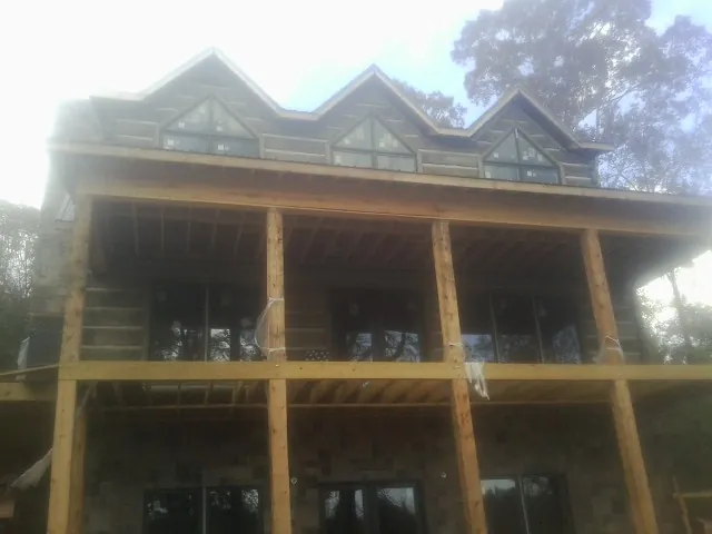 Dormers and porch framing on a large log home under construction — Roof Coating work by our crew in Sabin