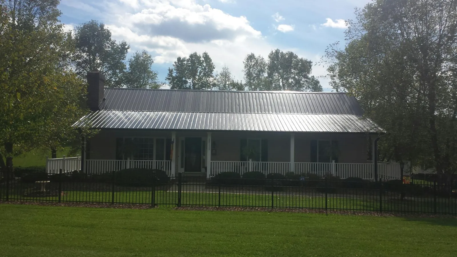 Gray metal roof on a brick ranch with a full width front porch — Gutter Guard Installation work by our crew in Sabin