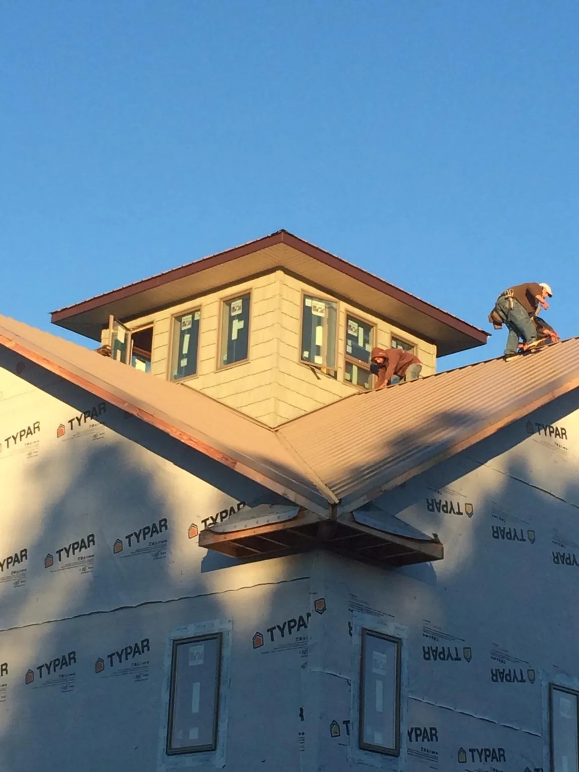 Roofers working around a rooftop cupola on a new metal roof at sunset — Roof Waterproofing in Sabin by Roofing Brothers